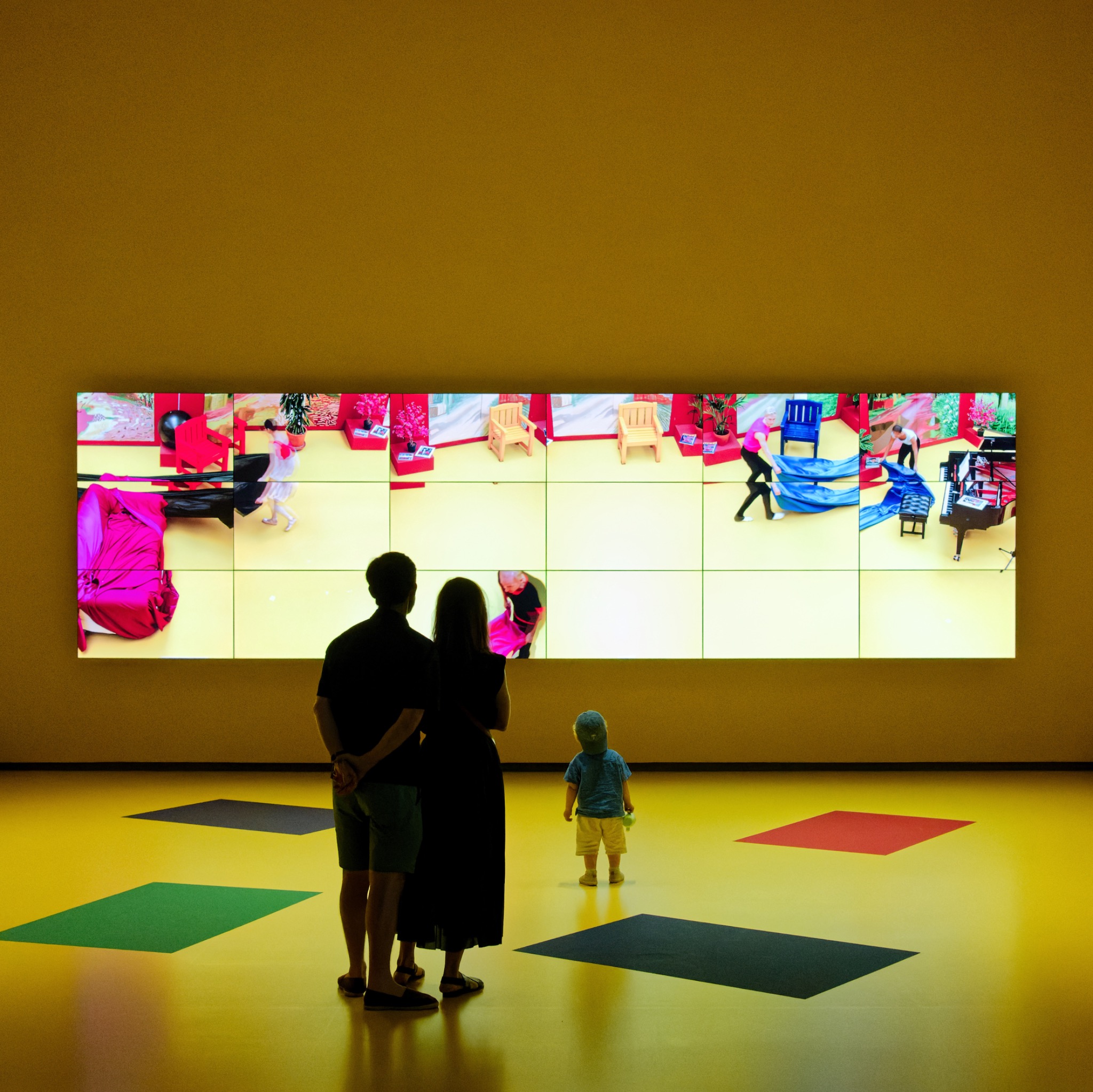 Drei Generationen vor einer leuchtenden Videoinstallation